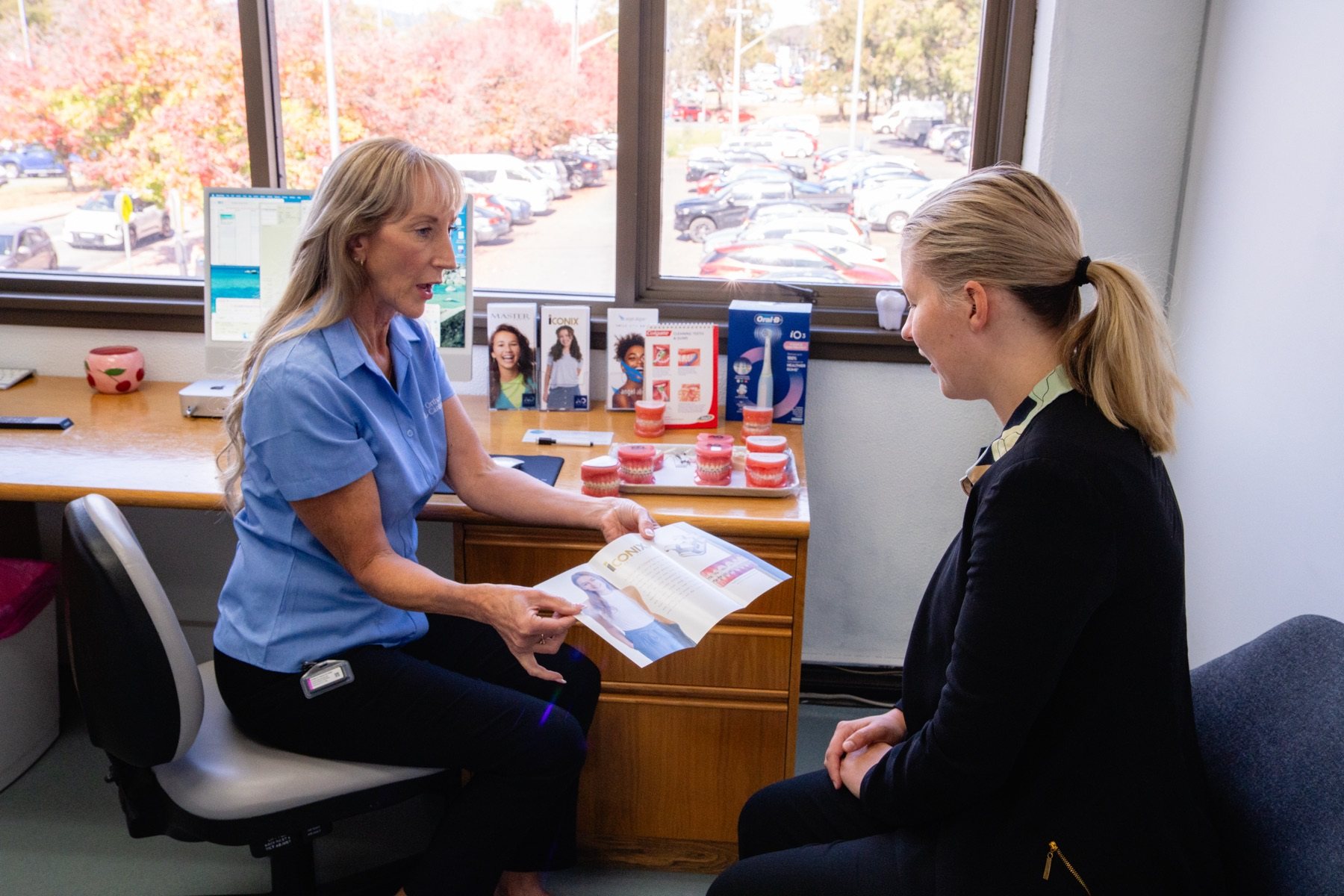 Orthodontist consulting with a young patient and showing treatment options